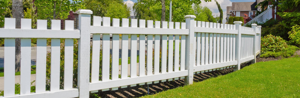 White picket fence along the edge of a green lawn